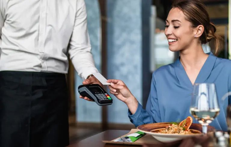 how do card readers work? Woman in restaurant paying by card on contactless card reader